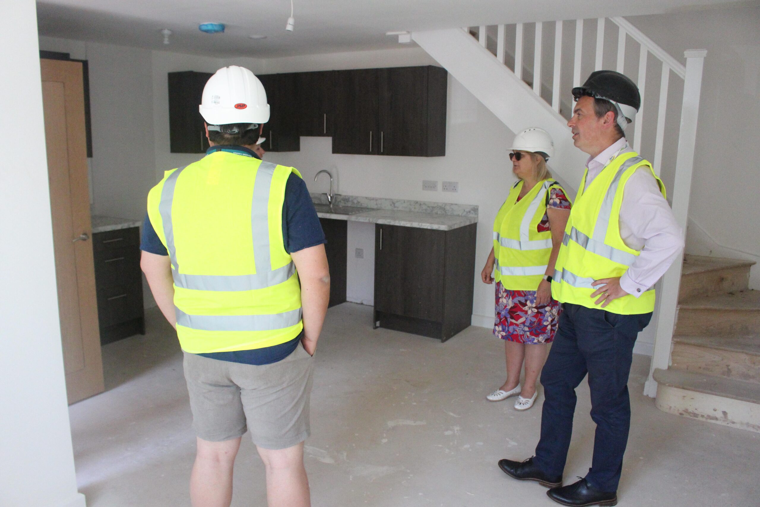 People stood inside a new build wearing safety equipment.