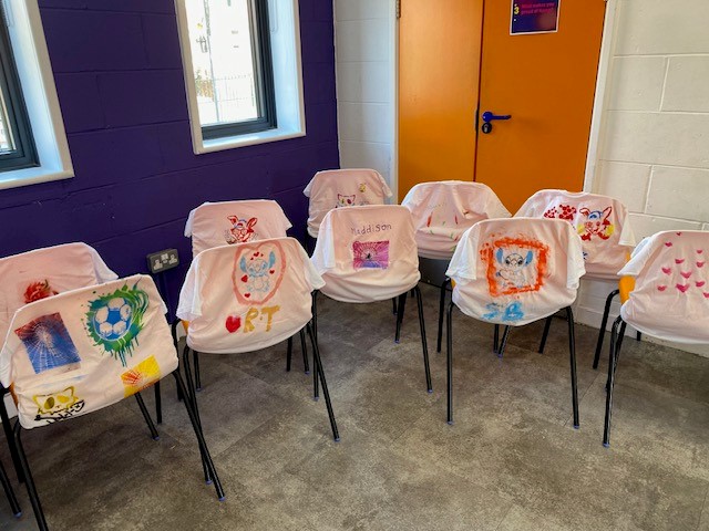 T-Shirts painted by the children living in Hamp, Somerset, displayed on some chairs inside the community hub.